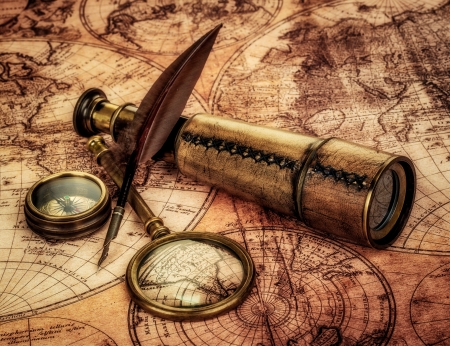 Vintage magnifying glass, compass, goose quill pen and spyglass lying on an old map.の写真素材