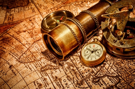 Vintage compass, , spyglass and a pocket watch lying on an old map.の写真素材