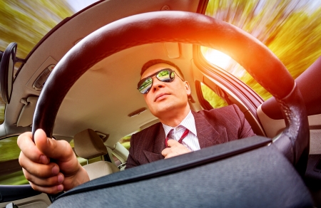 Man in a suit and sunglasses driving on a road in the car.の写真素材