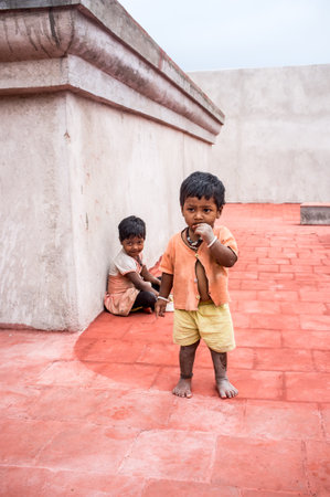 THANJAVUR, INDIA - FEBRUARY 14: Unidentified children, a boy and a girl on the roof of the temple February 14, 2013 in Thanjavur, India. Poverty in India is widespread, a third of the world's poor.のeditorial素材