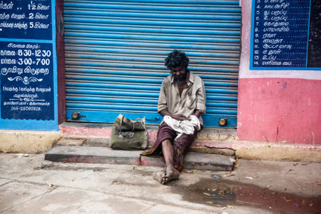 THANJAVUR, INDIA - FEBRUARY 14: Beggar sitting on a street February 14, 2013 in Thanjavur, India. Poverty in India is widespread, with the nation estimated to have a third of the world's poor.のeditorial素材