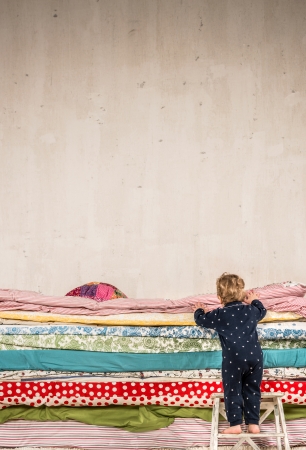 Child climbs on the bed with lots of quilts - Princess and the Pea.の写真素材