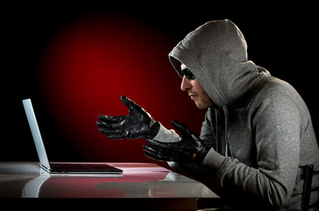 Hacker in a sunglasses with laptop.