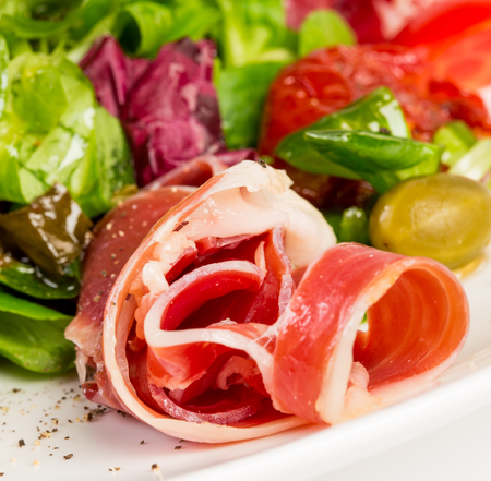 Raw bacon on a plate with vegetables and arugulaの写真素材