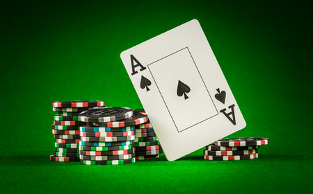 Stack of chips and two aces on the table on the green baize - poker game concept