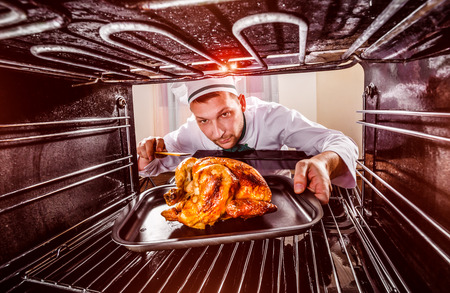 Chef prepares roast chicken in the oven, view from the inside of the oven. Cooking in the oven.