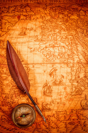 Vintage compass and goose quill pen lying on an old map in 1565.の写真素材