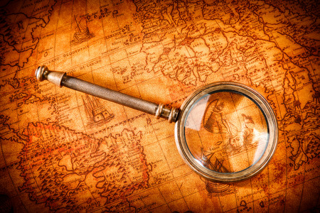 Vintage still life. Vintage magnifying glass lies on an ancient world map in 1565.