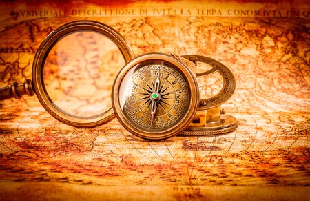 Vintage still life. Vintage magnifying glass and compass lies on an ancient world map in 1565.