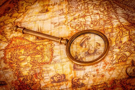Vintage still life. Vintage magnifying glass lies on an ancient world map in 1565.の写真素材