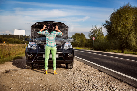 Woman on the road near the car. Damage to vehicle problems on the road.の写真素材