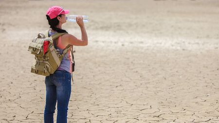 Traveller drinking water from bottle in the desertの写真素材