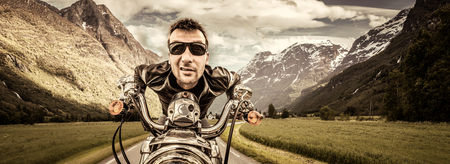 Funny Biker in sunglasses and leather jacket racing on mountain serpentine. Filter applied in...