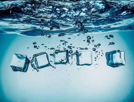 Ice cubes falling into the water sinking to the bottom. Abstract background.の写真素材