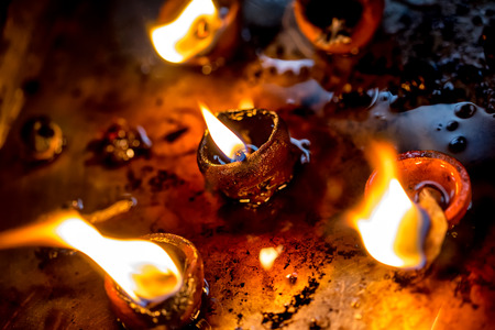 Burning candles in the Indian temple. Diwali the festival of lights. Warning - authentic shooting with high iso in challenging lighting conditions. A little bit grain and blurred motion effects.の写真素材