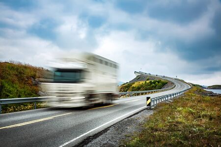 Truck and highway at sunset. Truck Car in motion blur. Atlantic Ocean Road or the Atlantic Road (Atlanterhavsveien) been awarded the title as "Norwegian Construction of the Century".の写真素材