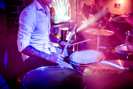 Drummer playing on drum set on stage. Warning - Focus on the drum, authentic shooting with high iso...