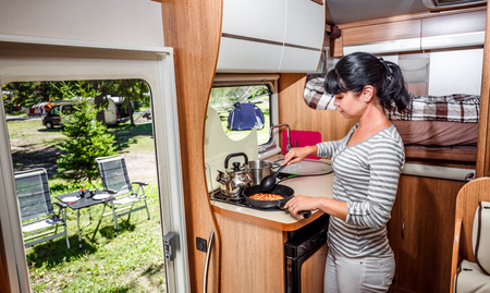Woman cooking in camper, motorhome interior. Family vacation travel, holiday trip in motorhome, Caravan car Vacation.の写真素材