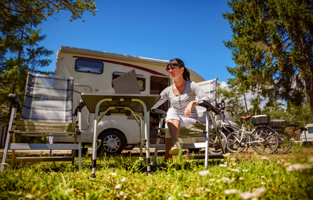 Woman looking at the laptop near the camping . Caravan car Vacation. Family vacation travel, holiday trip in motorhome. Wi-fi connection information communication technology.の写真素材