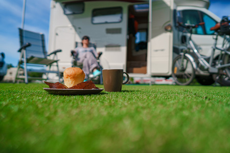 Muffin and Coffee Mug on grass. Caravan car Vacation. Family vacation travel, holiday trip in...