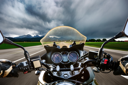 Biker on a motorcycle hurtling down the road in a lightning storm - Forggensee and Schwangau, Germany Bavariaの写真素材