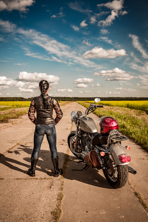 Biker girl stands on the road and looks into the distanceの写真素材
