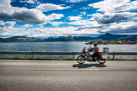 Biker rides a road with Atlantic Road in Norway. Atlantic Ocean Road or the Atlantic Road (Atlanterhavsveien) been awarded the title as "Norwegian Construction of the Century". Biker in motion blur.の写真素材
