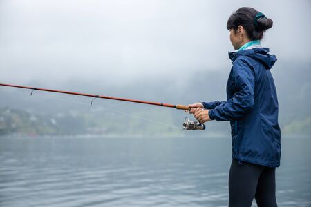 Woman fishing on Fishing rod spinning in Norway.