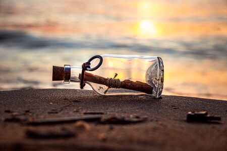 Message in the bottle against the Sun setting downの写真素材
