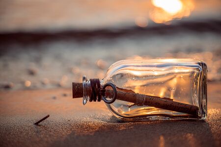 Message in the bottle against the Sun setting downの写真素材