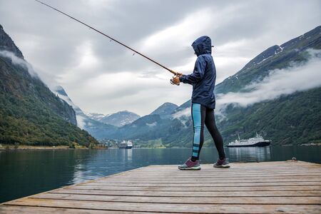 Woman fishing on Fishing rod spinning in Norway. Fishing in Norway is a way to embrace the local...