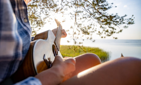 Woman at sunset playing the ukuleleの写真素材