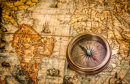 Vintage still life. Vintage compass lies on an ancient world map of 1565. Vintage style travel and...