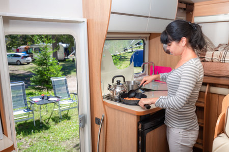 Woman cooking in camper, motorhome interior. Family vacation travel, holiday trip in motorhome RV, Caravan car Vacation.の写真素材