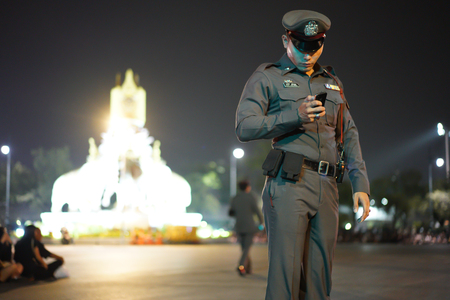 Thailand police are using smartphones in a ceremony to worship King Rama 9. He is checking the information for protecting people In the night of Bangkok.のeditorial素材
