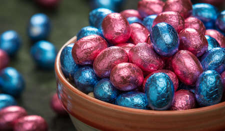 Bowl filled with ping and blue foil wrapped chocolate easter eggs.
