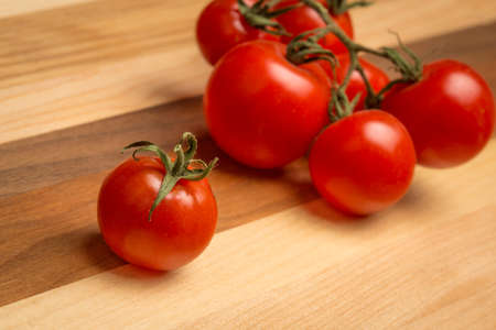Cherry tomatoes with stems on wooden cutting boardの写真素材