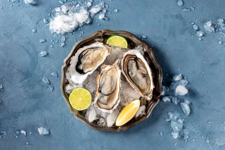 Oysters on ice, shot from the top on a slate, with lemon and limeの写真素材