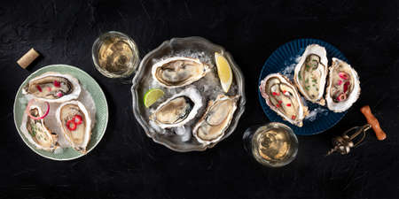 Oysters with various toppings panorama, shot from above with wine, with lemon and lime, pepper, onion, on a dark backgroundの写真素材
