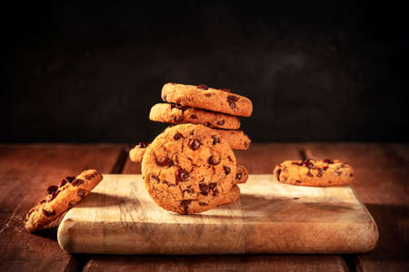 Chocolate chip cookies stack on a dark rustic wooden background