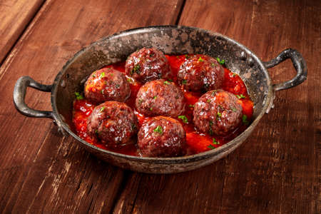Meatballs with tomato sauce, a close-up in a pan on a dark rustic wooden backgroundの写真素材