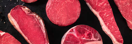 Red meat panorama. Raw beef steaks, shot from above on black