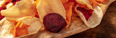 Vegetable chips panorama on a dark rustic wooden table