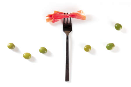 Ham on a fork with olives, shot from above on a white backgroundの写真素材