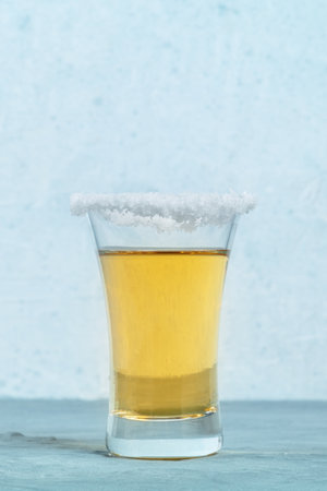 Golden tequila shot with a salt rim, a Mexican drink, side view with a place for textの写真素材