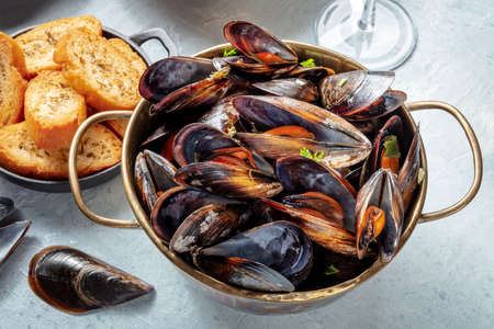 Cooked mussels in a copper pan, Belgian or French cuisine in a restaurant, with toasted breadの写真素材