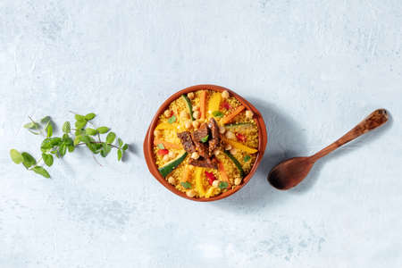 Couscous with meat and vegetables, festive Moroccan dinner, overhead flat lay shot with copy space, with fresh herbs and a wooden spoonの写真素材