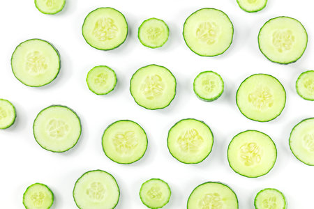 Fresh cucumber slices on a white background, overhead flat lay shot. Healthy organic food patternの写真素材