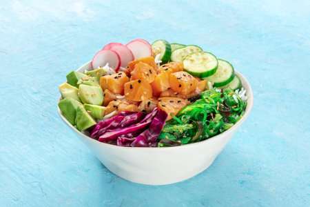 Salmon poke bowl with avocado, cucumbers, wakame, radish, and purple cabbage, a healthy Hawaiian dish with rice, on a blue backgroundの写真素材