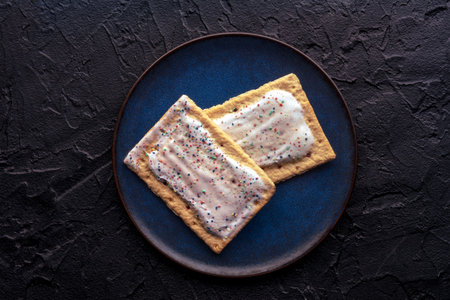 Pop tarts on a plate. Poptart toaster pastry with icing on a black slate background, overhead flat lay shotの写真素材